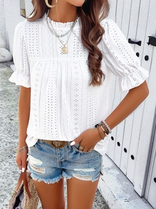 Detail of white hollow embroidered short sleeve top paired with denim shorts for beach vacation