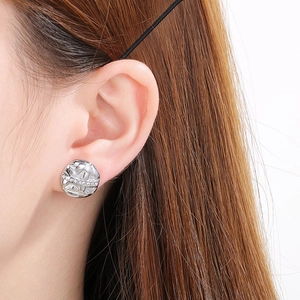 Detail shot of irregular silver stud earring with textured surface and pavé crystals
