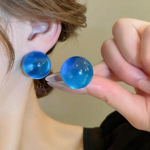 Minimalist blue round resin stud earrings for women shown on ear and held in hand