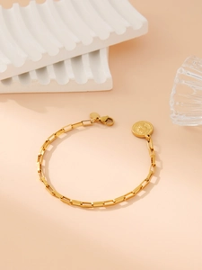 Macro detail of golden chain link bracelet with vintage coin pendant and lobster clasp
