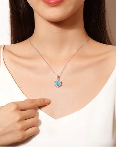 Nahaufnahme einer funkelnden blauen Schneeflocken-Anhänger Halskette mit silberner Kette.