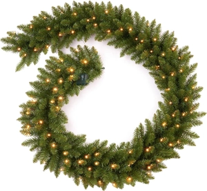 Macro view of 9ft green Christmas garland with warm white LED lights on a white background