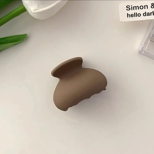 Detail view of a matte coffee brown small hair claw clip styled with elegant tulips