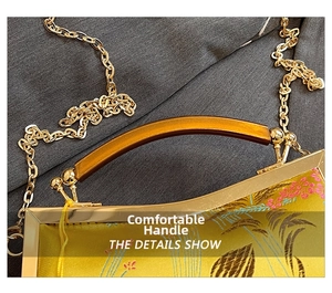 Detailed shot of yellow satin bag with flower embroidery, amber handle and gold chain
