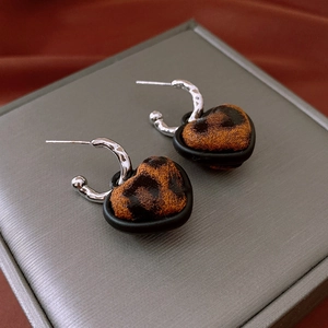 Detail shot of heart-shaped leopard print earrings with silver hammered texture hoops