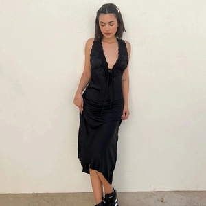 Détail d'une robe en satin noir avec décolleté en V profond, dos nu et lien de serrage avant