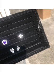 Gros plan de bagues violettes et blanches et boucles d'oreilles sur plateau velours