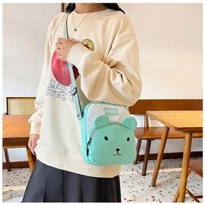 Close-up of mint green canvas crossbody bag featuring a cute bear design and fashion patch