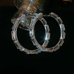 Macro shot of silver square-cut crystal rhinestones on large luxury hoop earrings