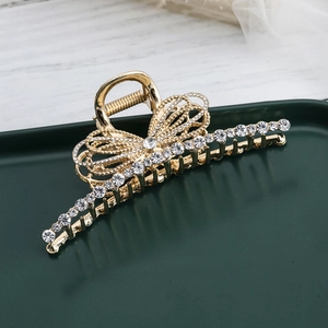 Detail of a gold butterfly hair claw clip featuring sparkling rhinestones and metal bow design