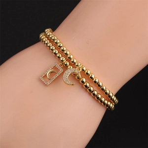 Detailed view of a gold double-layer beaded bracelet with crescent moon and square pendants