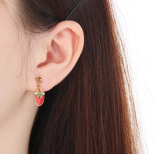 Close-up of a red strawberry pendant earring with green leaves on a golden stud