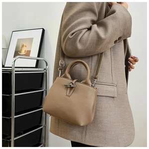 Detail of bamboo toggle closure on khaki leather mini bucket bag worn with a suit