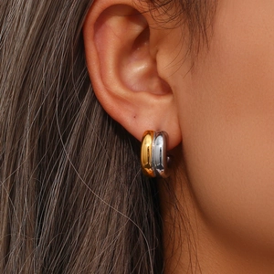 Close-up of gold and silver layered C-shaped earrings on a model with metallic finish