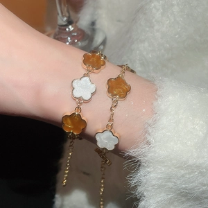 Gros plan détaillé de bracelets fleurs vintage dorés portés sur un pull en mohair doux