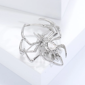 Macro shot of silver spider brooch with clear gemstone inlay on a white background