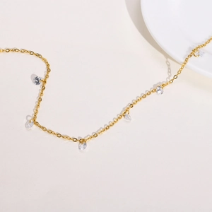 Macro shot of delicate gold necklace with clear zircon stones on a white ceramic plate