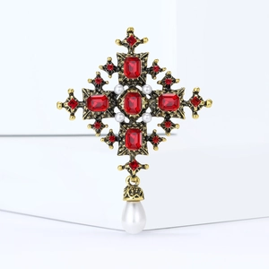 Detailed macro view of vintage baroque cross brooch with red gems and pearl drops