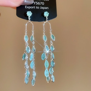 Detail of silver long fringe earrings featuring marquise-shaped light blue gemstones