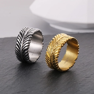 Close-up of gold and silver feather texture rings on a dark stone background