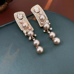 Detailed macro view of champagne artificial pearl drop earrings with sparkling rhinestones