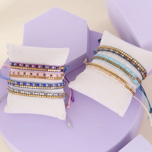 Bohemian handmade beaded bracelets with gold accents on white display cushions