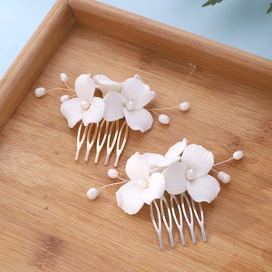 Elegant magnolia flower hair combs with white ceramic petals and pearls on wooden tray