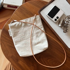Close-up of minimalist cotton linen crossbody bag with leather strap on a wooden table