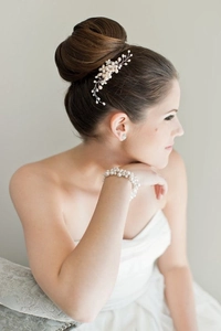 Detail of elegant bridal hair comb with pearls and crystals on a stylish bun hairstyle