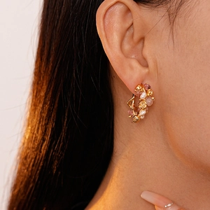 Detail of gold rose earring with pink strawberry crystal and pearls worn by a model