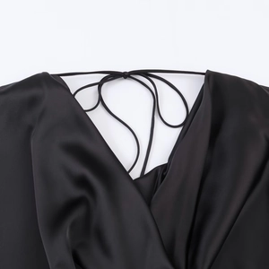 Detailed close-up of a black satin dress featuring a draped V-neck and delicate straps