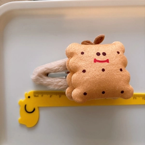 Cute biscuit plush hair clip with red smile embroidery and beige velvet backing