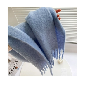 Close-up of sky blue fuzzy scarf with long tassels and soft brushed mohair texture