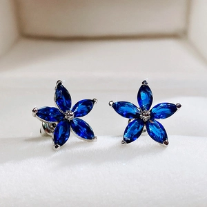 Detailed close-up of a blue five-petal flower stud earring with marquise-cut gems