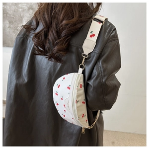 Close-up of white semi-circle fanny pack with cherry print and golden hardware on a model
