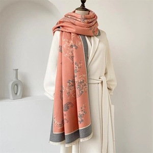 Détail d'une écharpe rose corail façon cachemire avec fleurs chinoises et franges élégantes