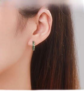 Close-up of S925 sterling silver hoop earrings with green crystals on female model