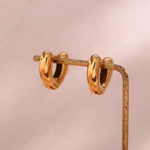 Detail of 18K gold-plated heart-shaped earrings on a vintage metal display stand
