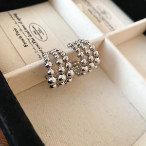 Detail of silver multi-layered beaded hoop earrings displayed in a beige jewelry case