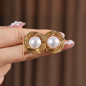 Macro view of gold vintage pearl earrings with spiral frame and white pearl center