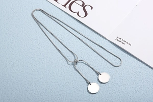 Detail of silver adjustable snake chain necklace with circular tags on a blue surface