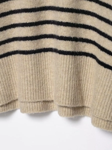 Vue détaillée du bord-côte doux sur un pull en maille rayé beige et noir de haute qualité