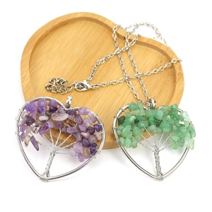 Handmade tree of life heart necklaces with purple and green crystal stones on wood tray