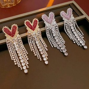 Detail of heart-shaped tassel earrings with pavé rhinestones in gold and silver