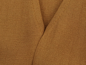 Close-up of brown woven fabric showing detailed grainy texture and V-stitch seam detail