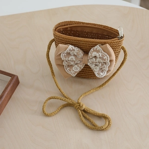 Detail der gewebten Strohtasche für Mädchen mit großer Spitzenschleife auf Holz