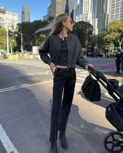 Close-up of a stylish dark grey tweed jacket paired with black straight-leg jeans in city