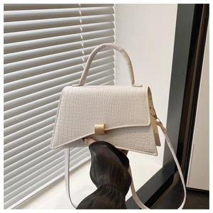 Detail of white crocodile pattern shoulder bag featuring asymmetric flap and gold buckle