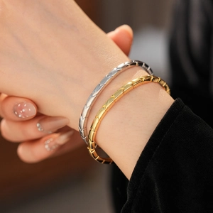 Detail of minimalist gold and silver bangles featuring a textured V-shape geometric pattern