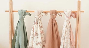Detail view of four layered cotton baby blankets with deer and floral prints on hangers